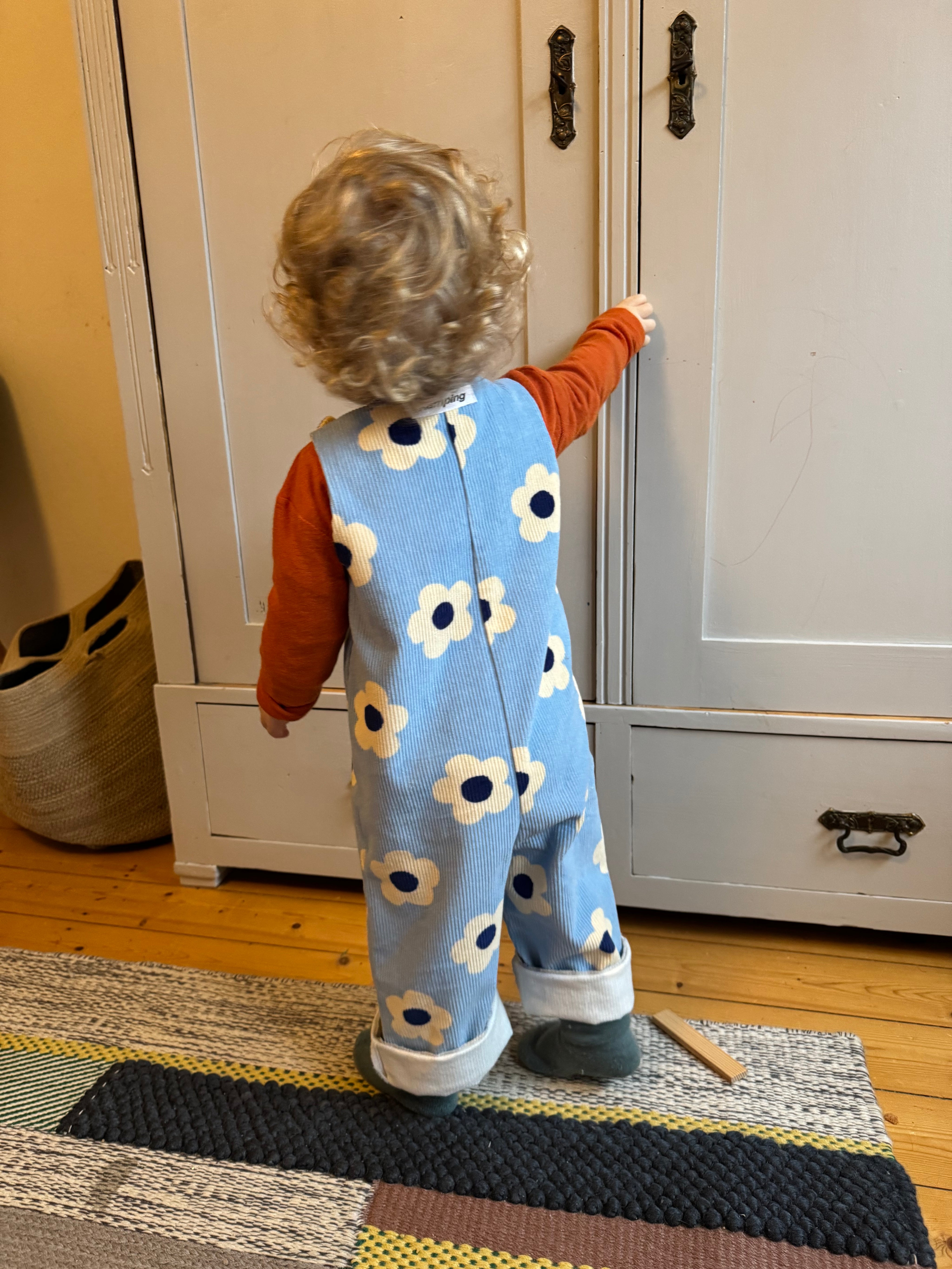 Kamping Studios - Baby Overall und Strampler mit blauen Blumen am Model, kleines Kind