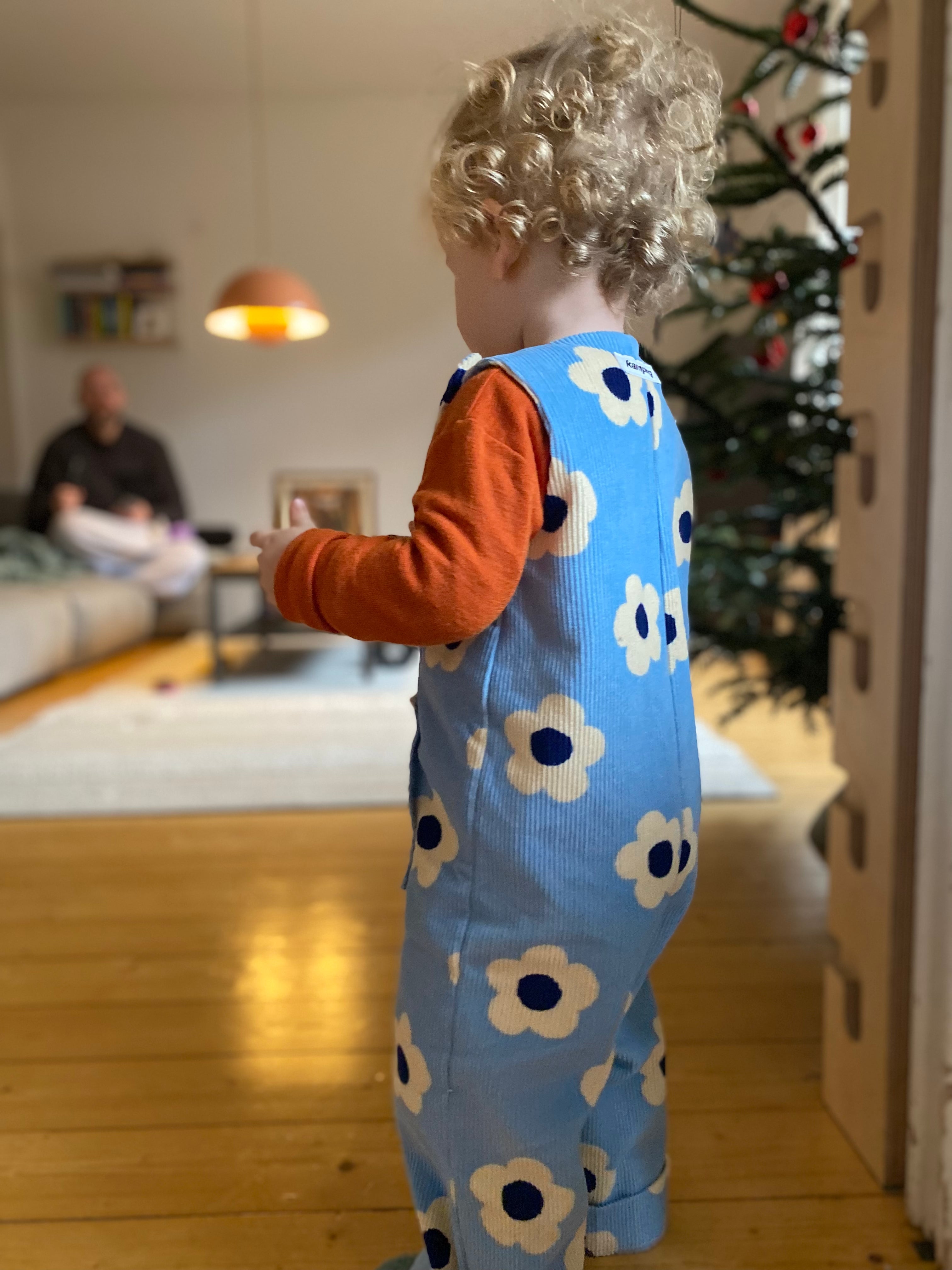 Kamping Studios - Baby Overall und Strampler mit blauen Blumen am Model, Seite