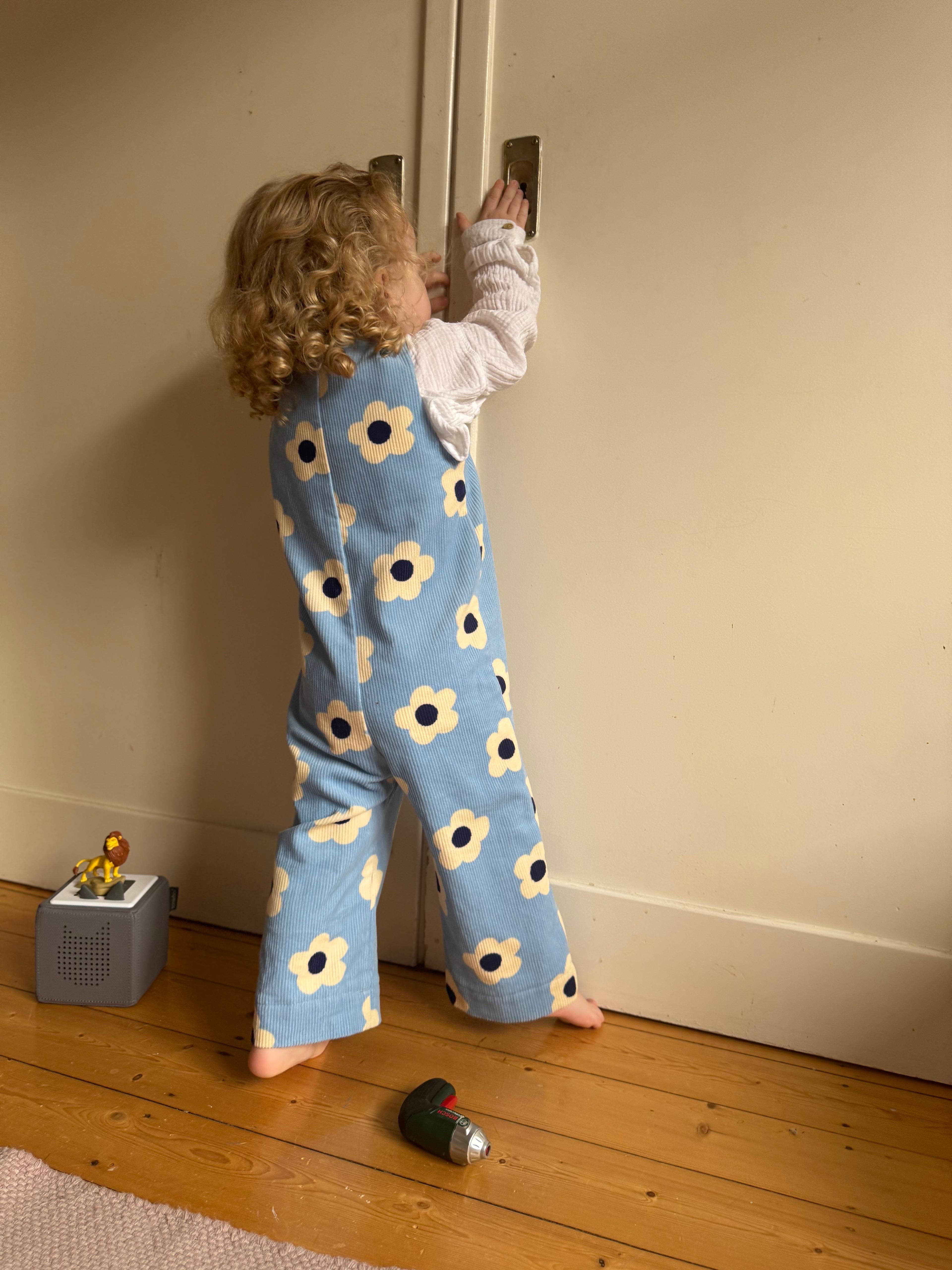 Kamping Studios - Baby Overall und Strampler mit blauen Blumen am Model, am spielen