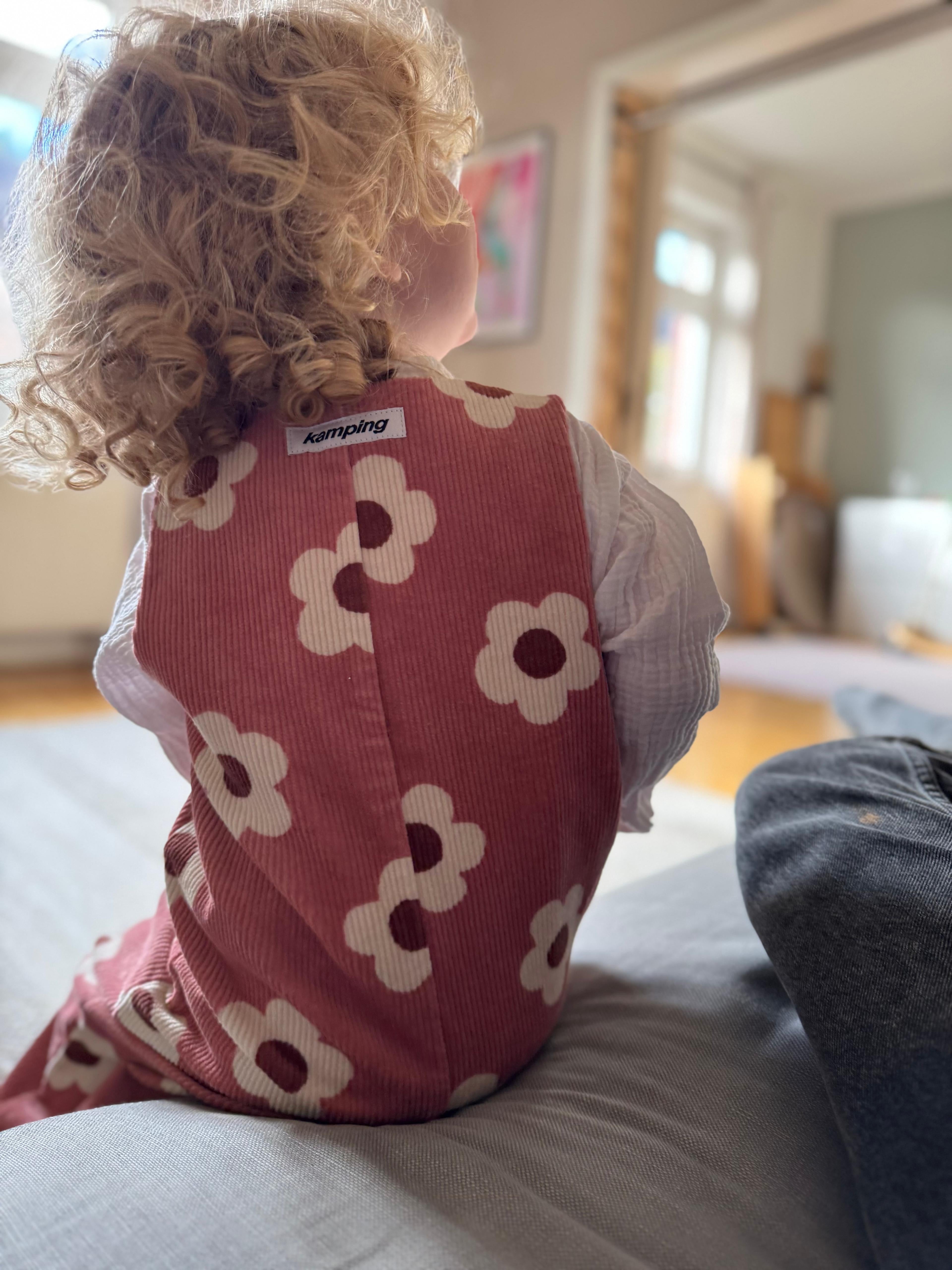 Baby Overall und Strampler mit rosa Blumen am Model, Rueckseite von Logo