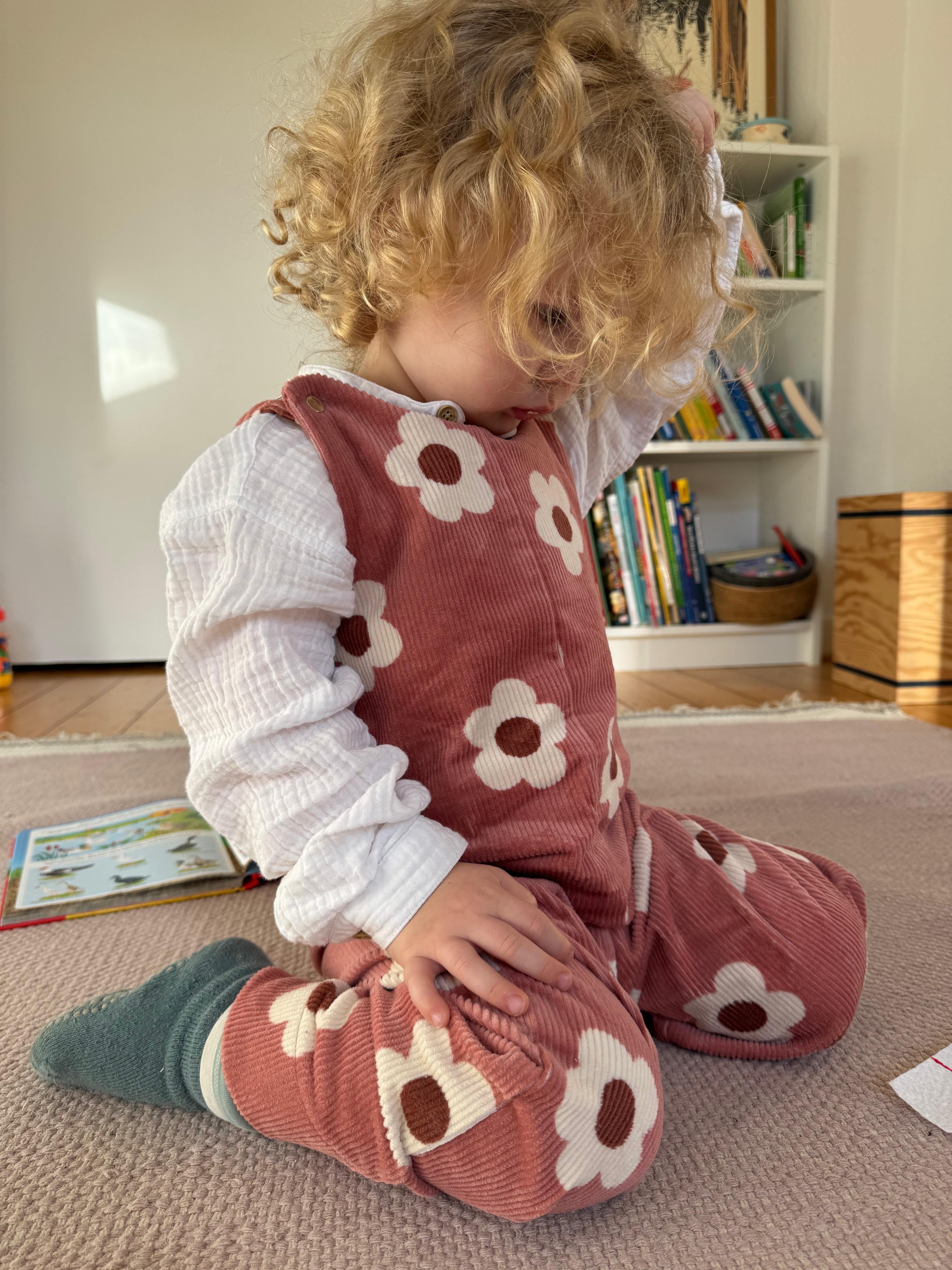 Baby Overall und Strampler mit rosa Blumen am Model, Vorderseite