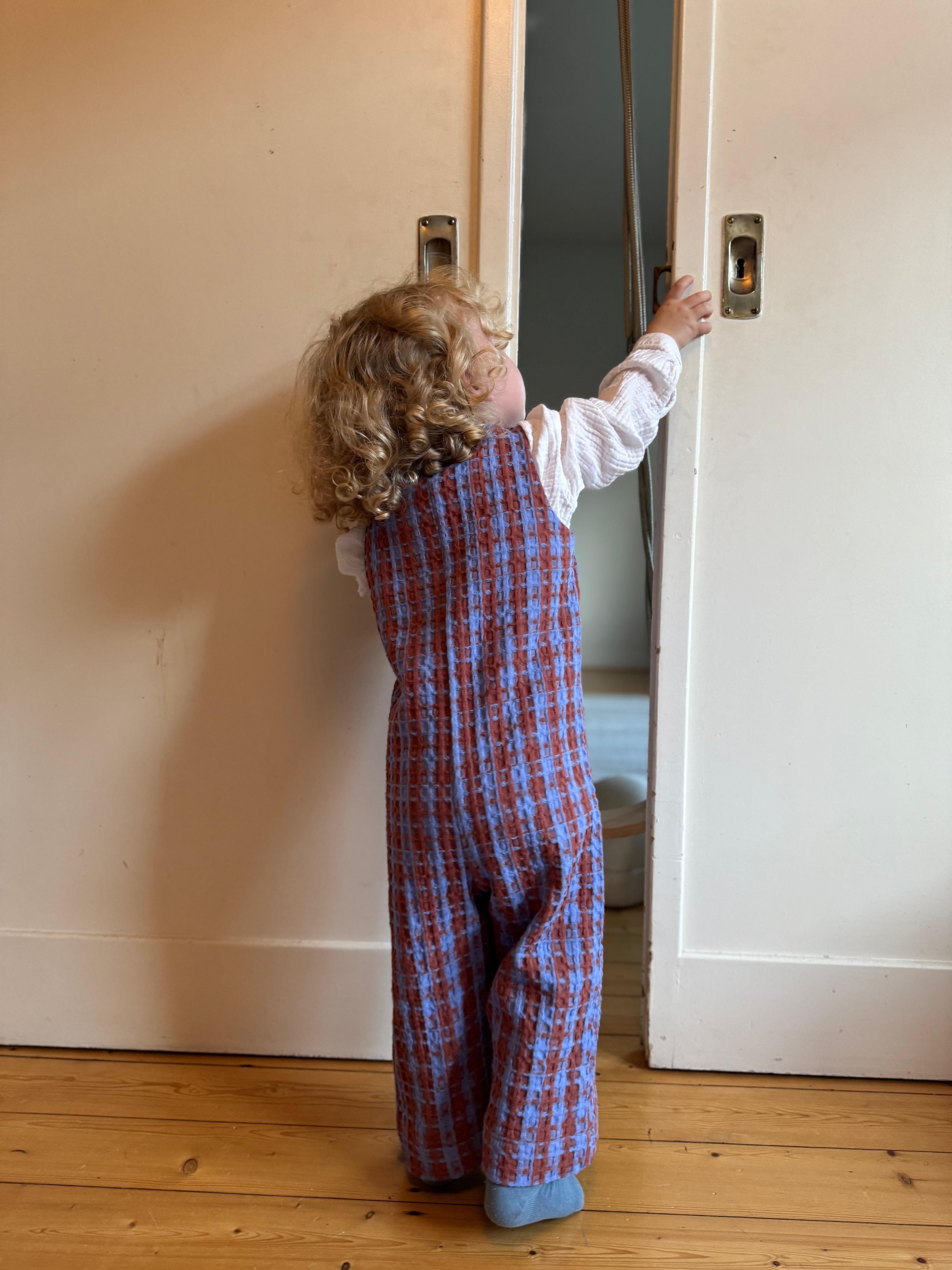 Kamping Studios Baby Overall und Strampler aus Baumwolle, kariert blau/rot am Model, Rueckseite